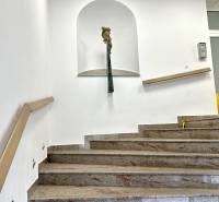 A staircase with marble steps, a railing, and a niche with a statue on the wall.