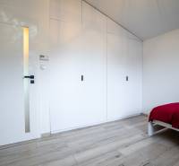 Bedroom in a family house with a white wardrobe, doors, and a bed with a colorful blanket.