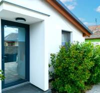 In Čierna Voda, there is a family house with a white facade surrounded by green shrubs.