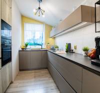 A kitchen in a family house with modern cabinets, appliances, and a bright window.