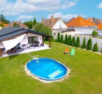 A family house in Čierna Voda with a swimming pool on a green lawn and a terrace.