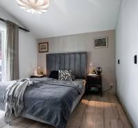 Bedroom in a family house with a bed, nightstands, and lamps, with a view outside.