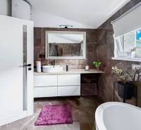Bathroom in a family house with a bathtub, sink, and window, decorative plants.