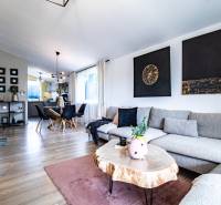 Living room in a family house with a gray sofa, wooden table, and dining area.