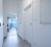 A narrow bright hallway in a family house with a view of the room and terrace.