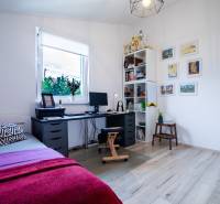 A workspace in a family house with a desk, bed, and a shelf with trophies.