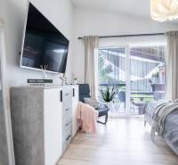 Bright bedroom in a family house with a TV, mirror, and balcony.