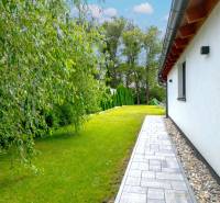 A family house in Čierna Voda with a well-maintained garden and a walkway alongside the building.