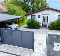 A family house in Čierna Voda with a car, a gate, and a landscaped garden.
