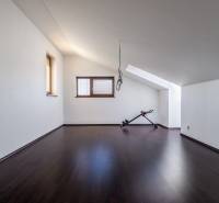An attic room in a family house with exercise equipment on a dark floor.