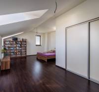 Attic bedroom with a bookshelf and a cabinet in a family house, dark floor.