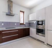 A kitchen in a family house with white and wooden cabinets and built-in appliances.