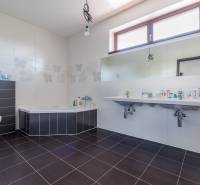 A bathroom in a family house with a bathtub, double sink, and toilet.