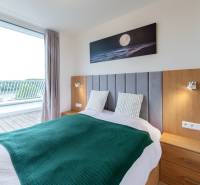 A bedroom in a 2-room apartment with a balcony, wooden furniture, and a painting of the moon.