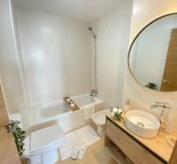 Bathroom in a 3-room apartment with a bathtub, toilet, and round mirror.