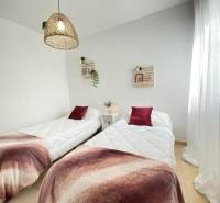 Two beds with bedspreads and decorative pillows in a 3-room apartment.
