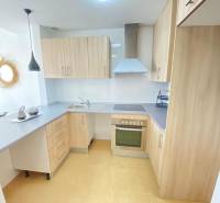 A kitchen in a 3-room apartment with wooden cabinets, a cooking area, and modern lights.