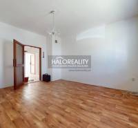 A spacious room with wooden flooring, a chandelier, and open doors in a family house.