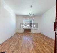 An empty room with a wooden floor and a chandelier, in a family house.