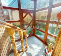 Wooden staircase with glass walls in a family house, equipped with garden tools.