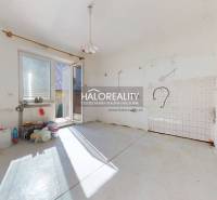 An empty room in a family house with a door to the terrace and preparation for a kitchen.