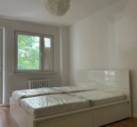 Bedroom in a 2-room apartment with large windows and a double bed.