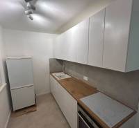 Kitchen unit with a cooktop and oven in a 2-room apartment, simple white design.