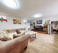 Living room with a sofa, wooden floor, and decorative paintings in a family house.