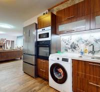 A kitchen in a family house with wooden cabinets, a dishwasher, and decorative tiles.