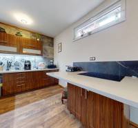 A kitchen in a family house with brown cabinets and floral tiles.