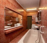 A bathroom with pink tiles, a bathtub, a sink, and a mirror in a family house.