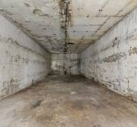An abandoned concrete space in a family house, with peeling plaster and exposed wires.