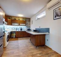 A kitchen in a family house with wooden furniture, appliances, and air conditioning.