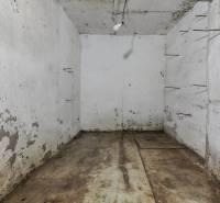 A worn-out basement in a family house with lighting and metal protrusions on the wall.