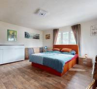 Bedroom in a family house with a bed, a dresser, and a window with curtains.