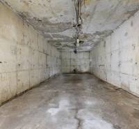 A concrete room in a family house with peeling plaster and simple lighting.