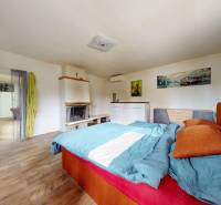 Bedroom in a family house with a fireplace, bed, and wooden floor.