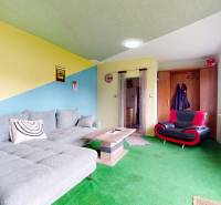 Living room in a family house with an upholstered sofa, an armchair, and a wooden table.