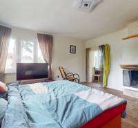 Bedroom in a family house with a fireplace, bed, and large window.