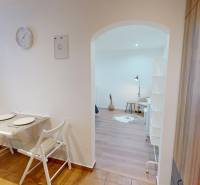 A dining nook with two chairs leads into the living room in a studio apartment.