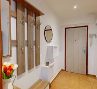Hallway with a coat rack, mirror, and flowers, furnishing of a studio apartment.