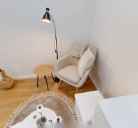 Armchair with a cushion, small table, lamp, and decoration in a studio apartment.