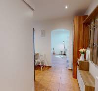 A hallway with a coat rack and a mirror in a studio apartment continues into the living area.