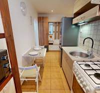 A kitchen in a studio apartment equipped with a microwave, table, and stovetop.