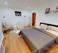 A bedroom in a studio apartment with a bed, an armchair, and decorations.