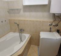A bathroom in a 2-room apartment with a bathtub, boiler, and washing machine.