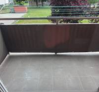A balcony with a tiled floor and a view of greenery in a 2-room apartment in Liptovský Mikuláš.