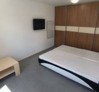 A bedroom with a double bed, a television, and a built-in wardrobe in a 2-room apartment.