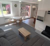 Living room in a two-room apartment with a sofa, television, and dining table.