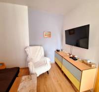 Living room in a three-room apartment, with a TV on the wall and comfortable armchairs.